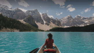 Woman paddling in canoe looking at Canadian mountain range