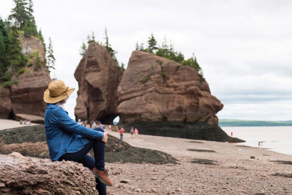 A woman looking at the rocks at Hopewell Rocks in NB, Canada